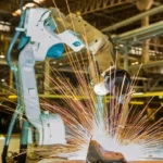 Welder performing MIG welding on metal components in a shop.
