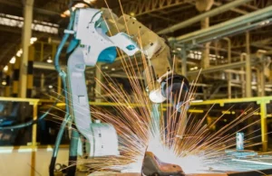 Welder performing MIG welding on metal components in a shop.