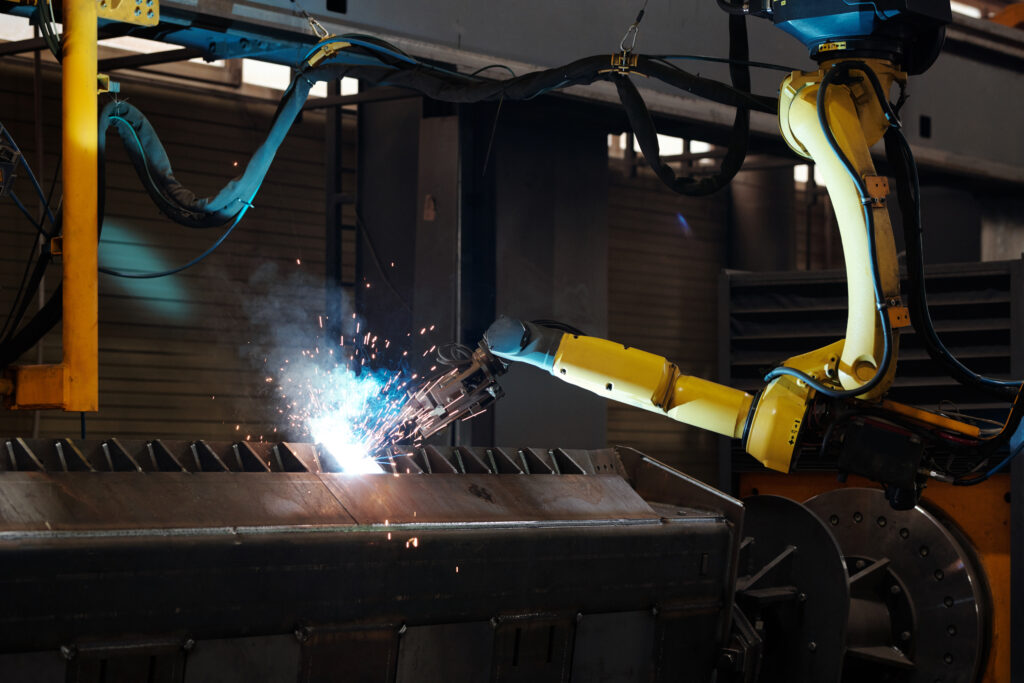 Automated robotic arm arc welding industrial metal frame.